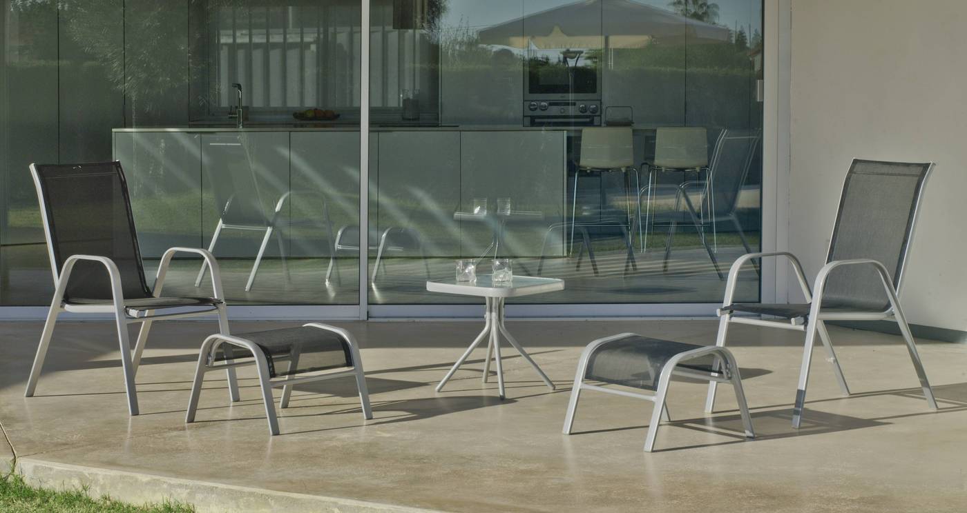 Conjunto de acero inoxidable color plata: mesa auxiliar con tablero de cristal templado + 2 sillones apilables de acero y textilen + reposapies